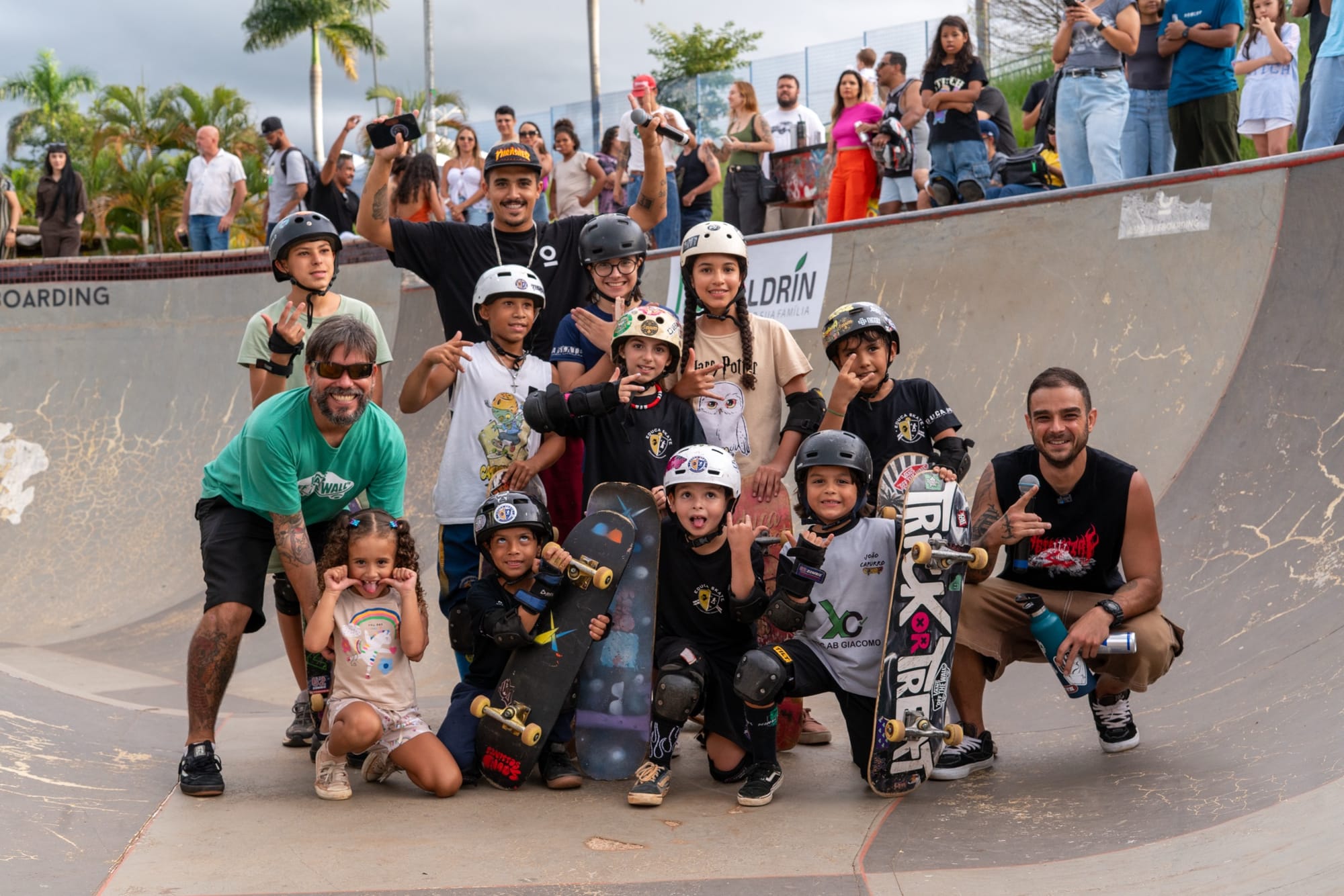 Crianças e adolescentes com capacetes e skates posam em grupo dentro do bowl