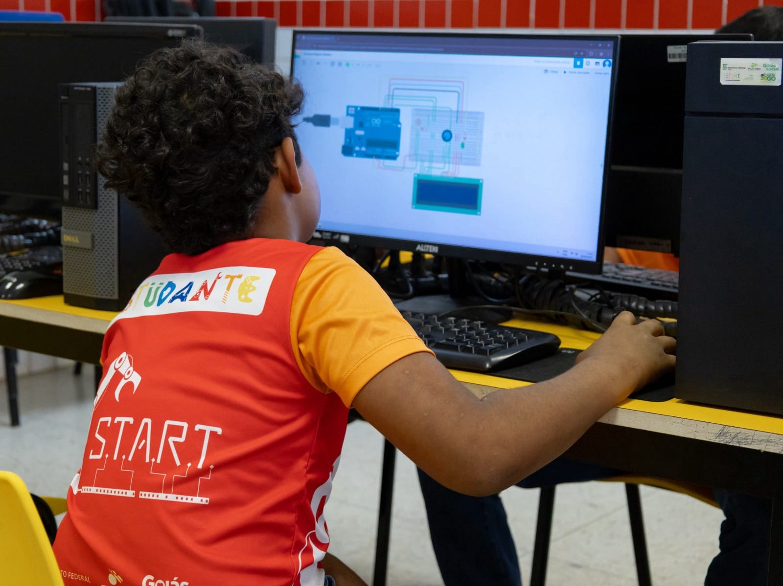 Criança olhando monitor com diagrama de circuito Arduino