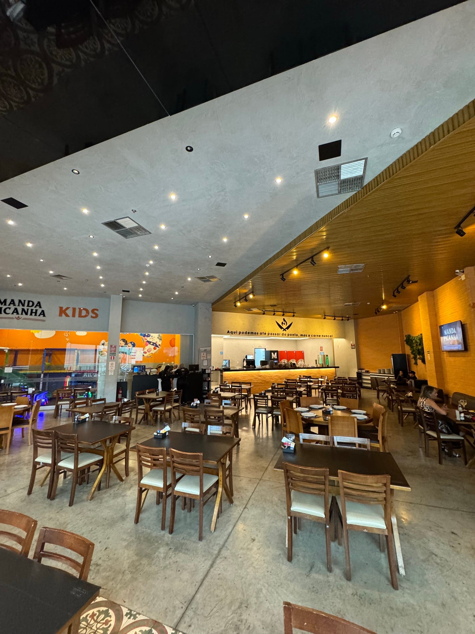 Salão interno do restaurante Manda Picanha com mesas e iluminação