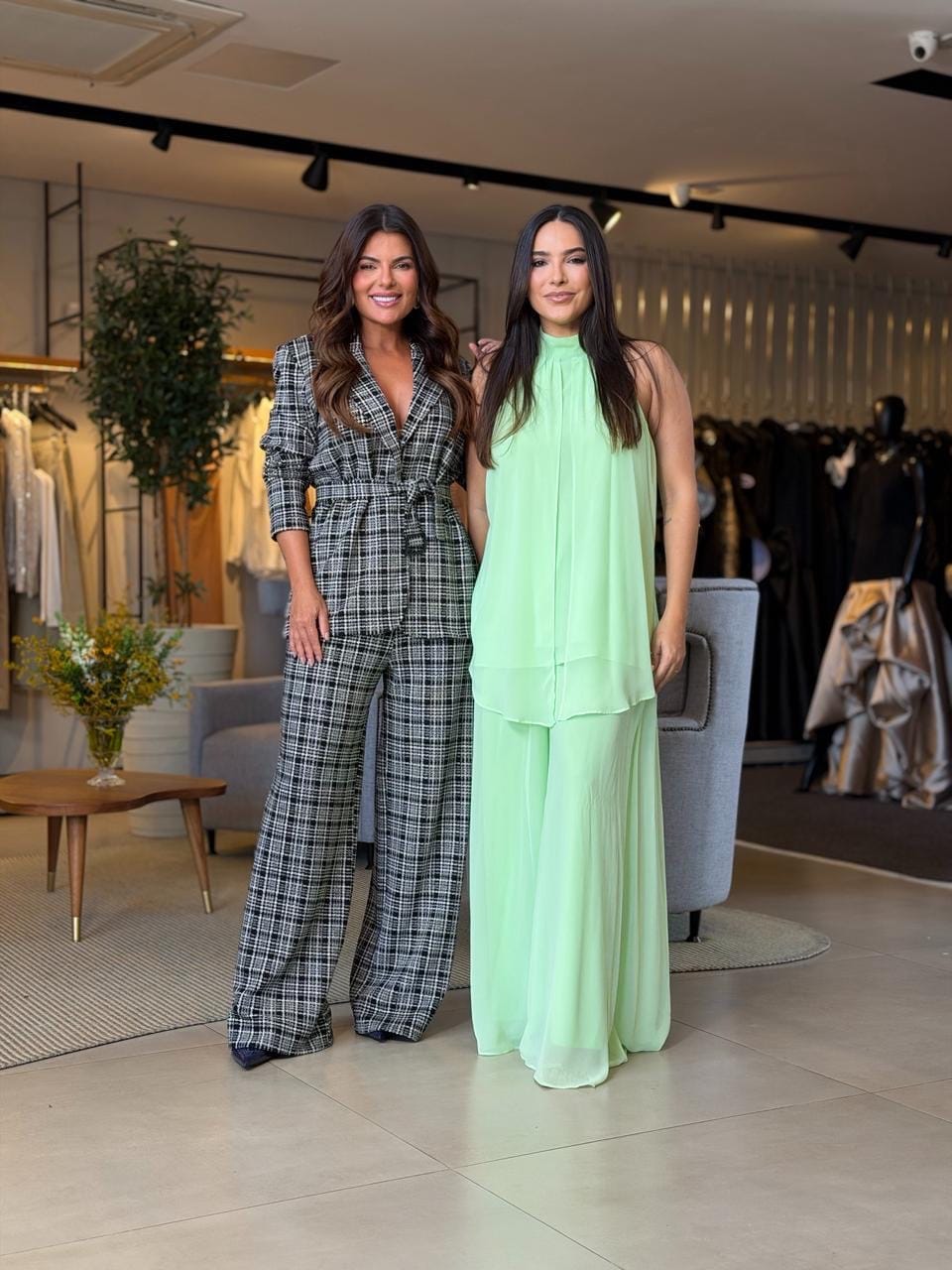 Duas mulheres posam sorrindo no interior da loja durante o evento