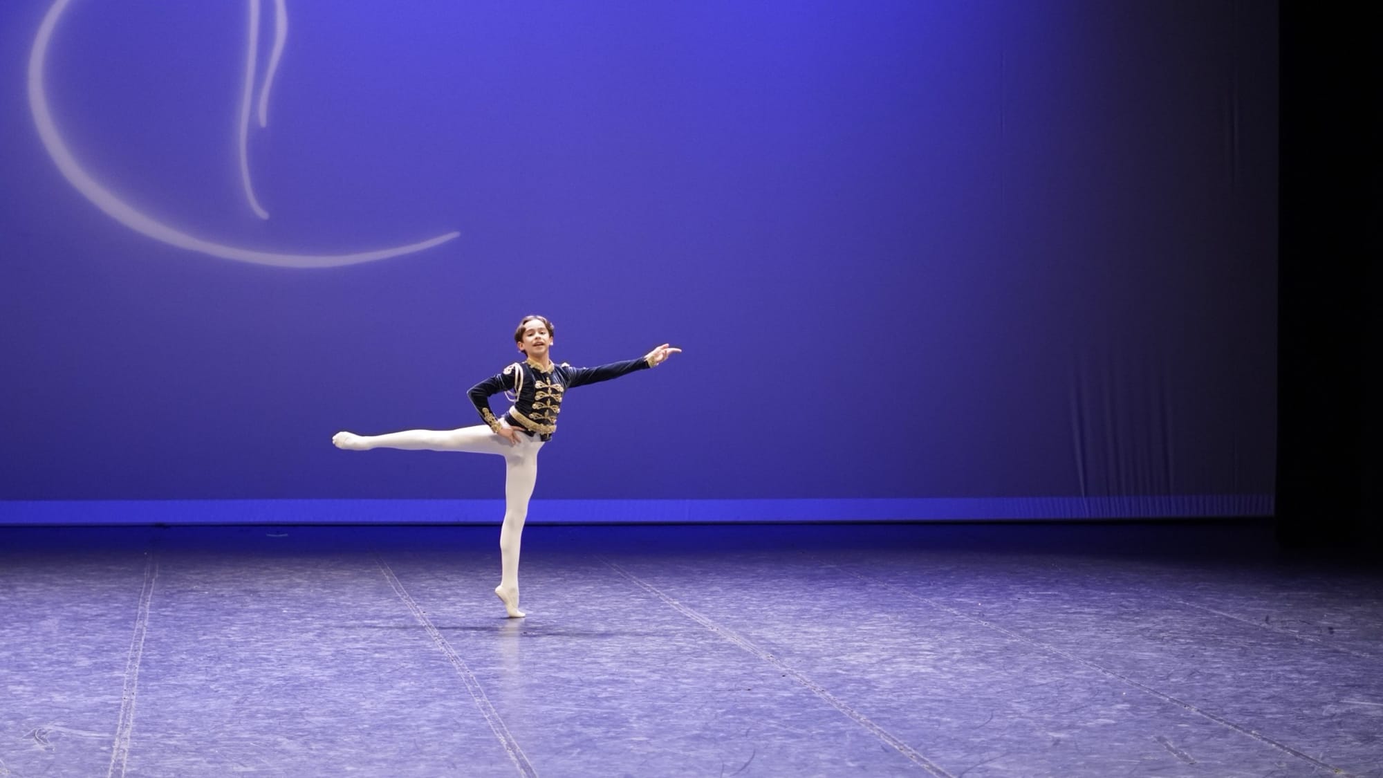 Bailarino júnior em posição de equilíbrio no palco