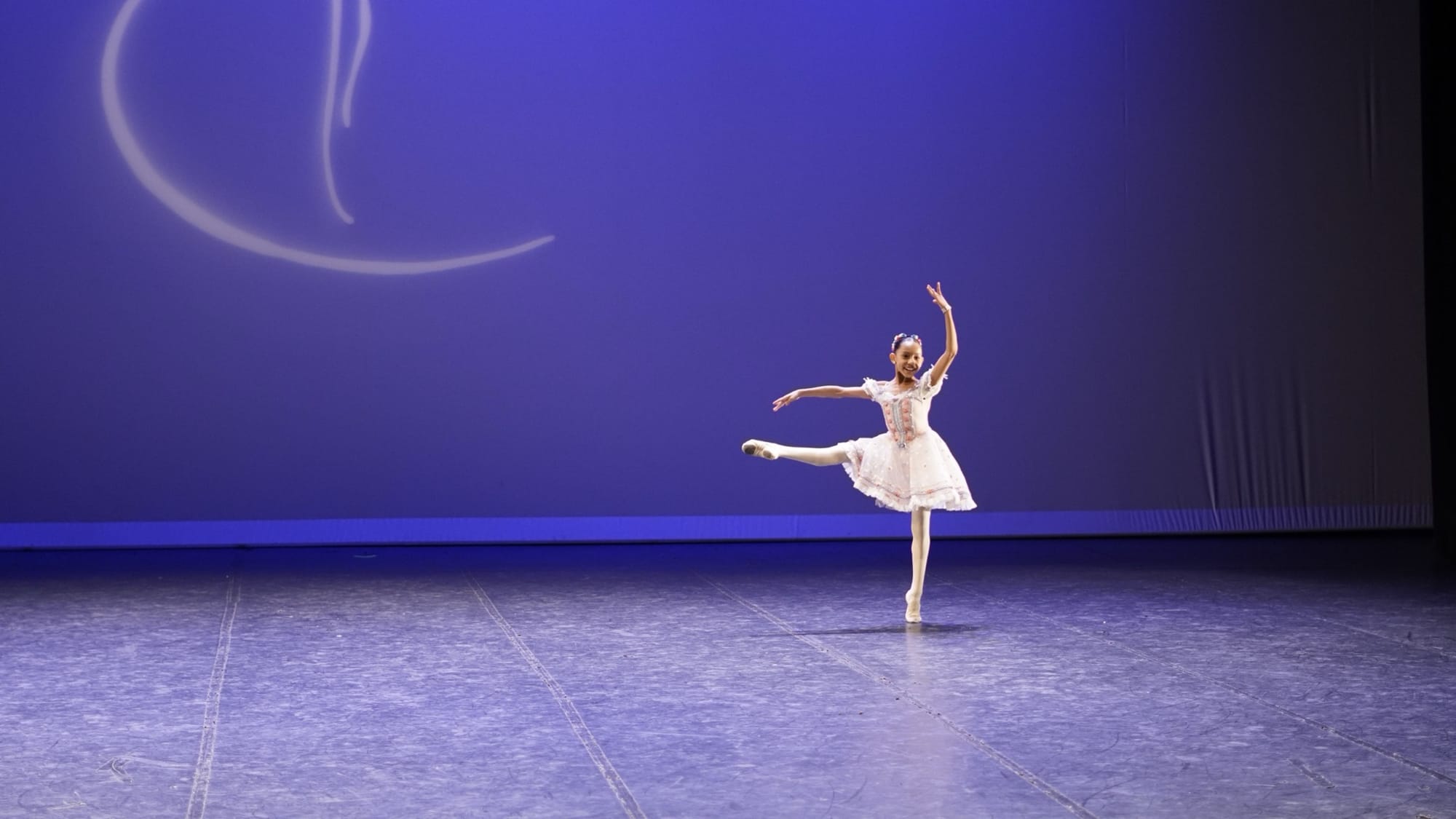 Bailarina jovem em posição de dança no palco