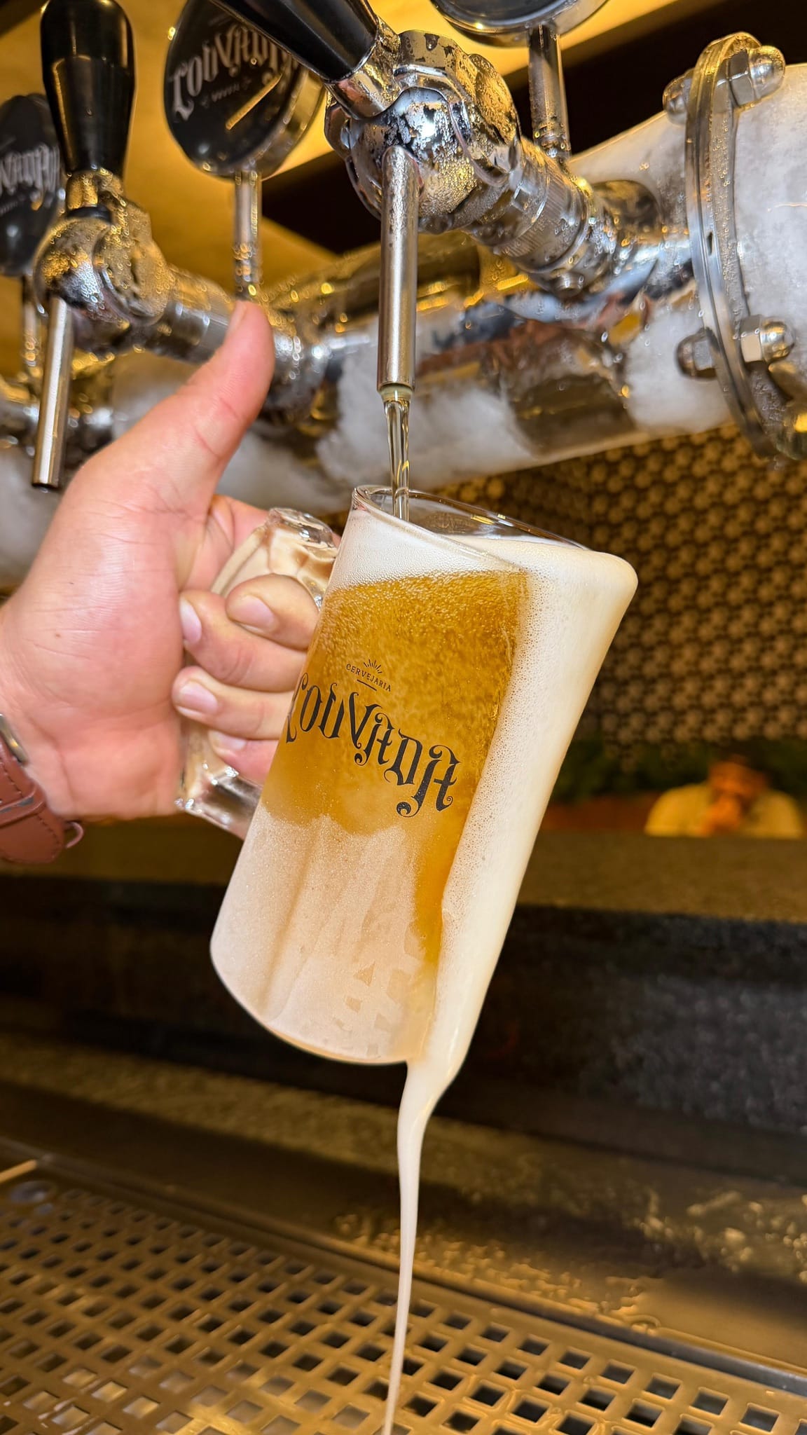 Caneca sendo preenchida com chope claro da torneira da Cervejaria Louvada