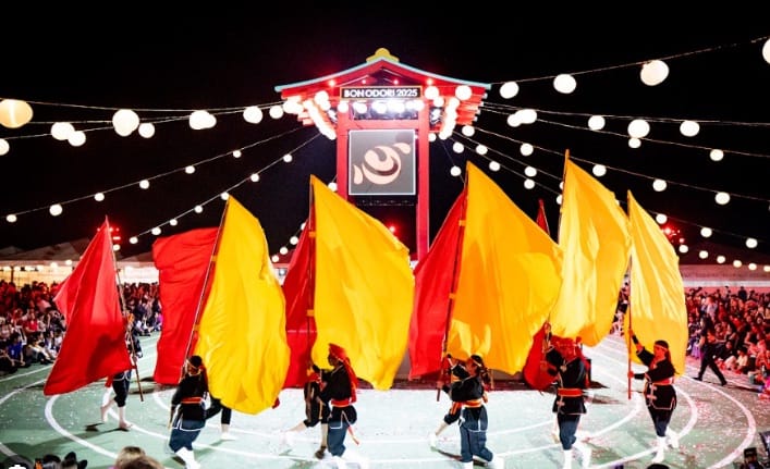 Grupo de dança com grandes bandeiras vermelhas e amarelas