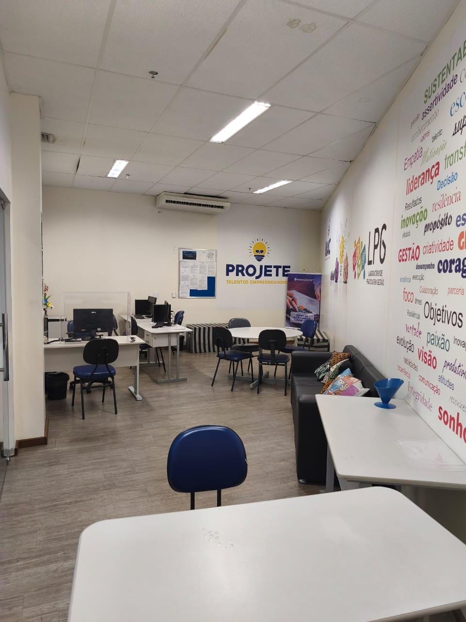 Sala de atendimento com mesas, cadeiras e computadores