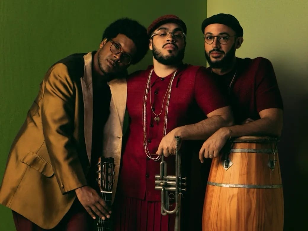 Trio musical posando com instrumentos em estúdio