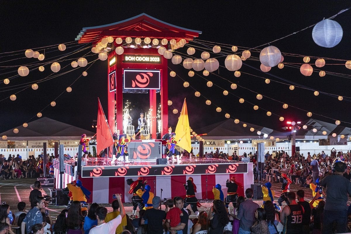 Palco iluminado com artistas em apresentação noturna