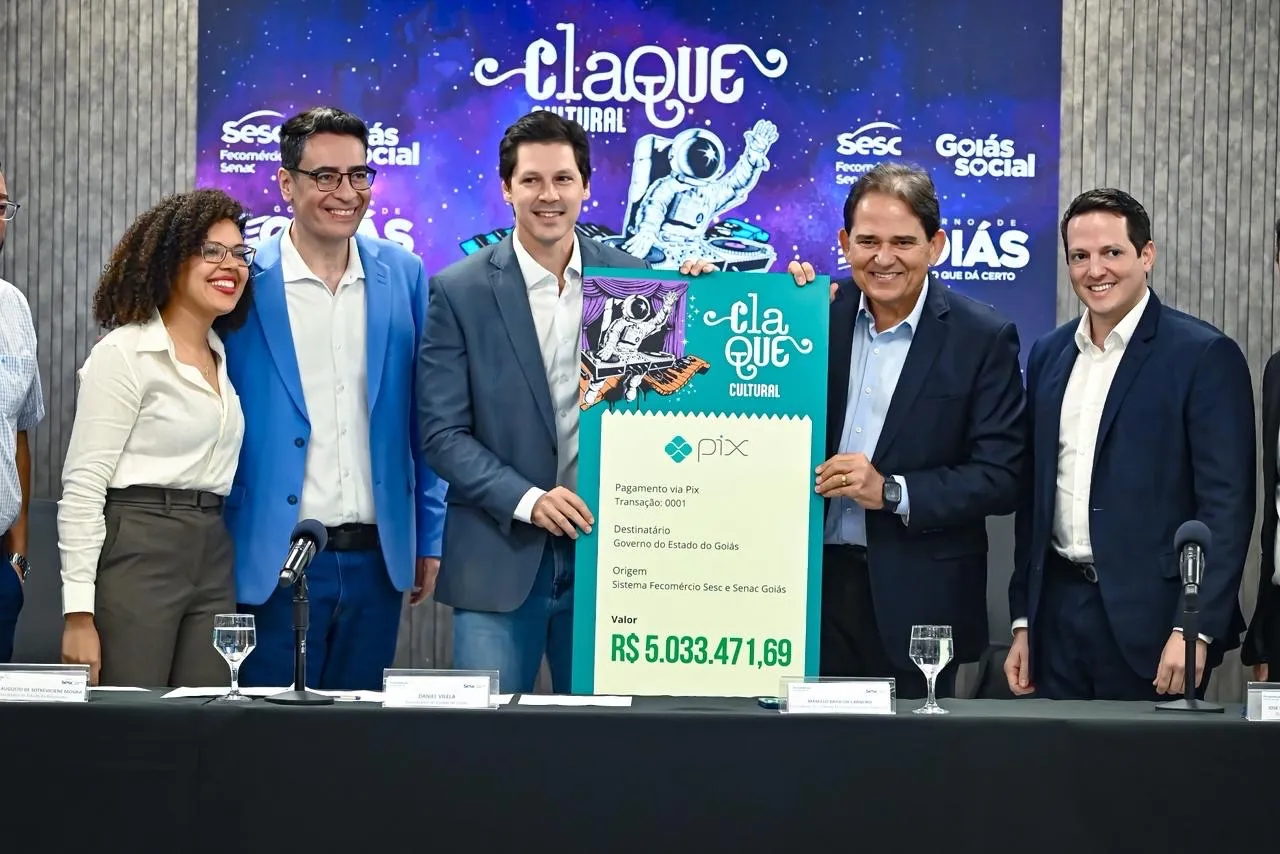 Autoridades segurando cheque simbólico do Claque Cultural durante cerimônia de encerramento