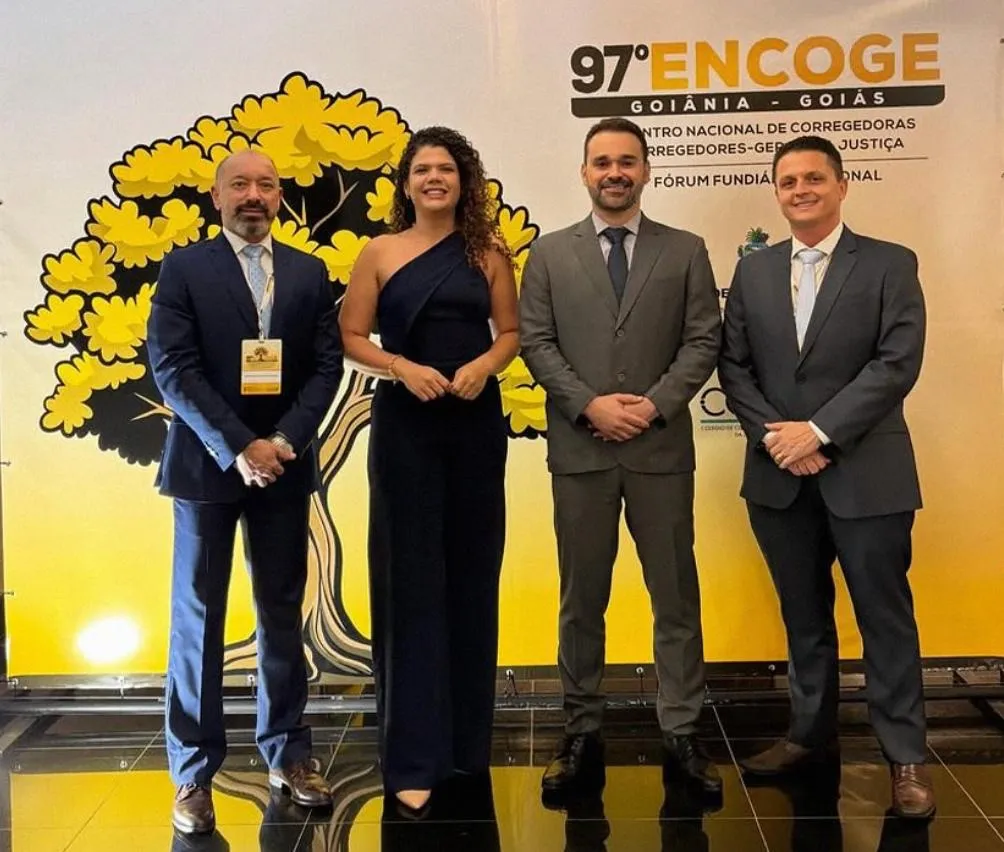Participantes do 97º ENCOGE e do 9º Fórum Fundiário Nacional posam em frente a painel do evento em Goiânia
