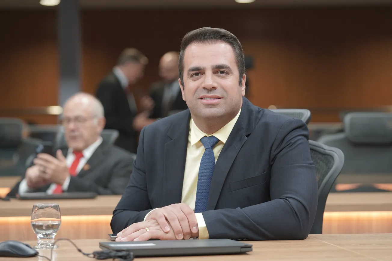 Parlamentar sentado em plenário, trajando terno e gravata