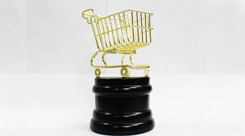 Troféu em forma de carrinho de compras dourado sobre base preta