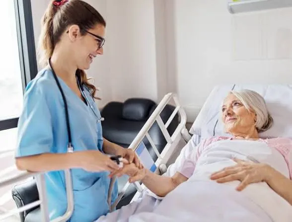 Enfermeira segurando a mão de paciente idosa em leito hospitalar