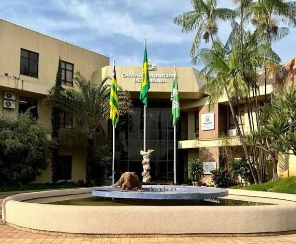 Fachada da Câmara Municipal de Goiânia com bandeiras e fonte na frente
