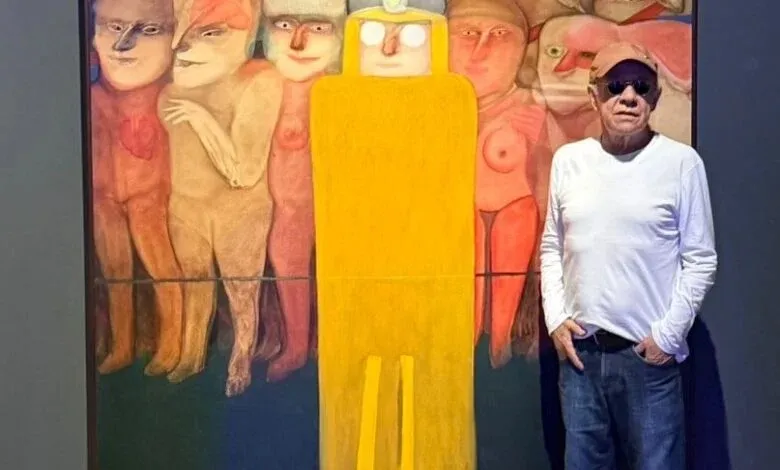 Siron Franco posando ao lado de uma de suas obras na exposição Expressões