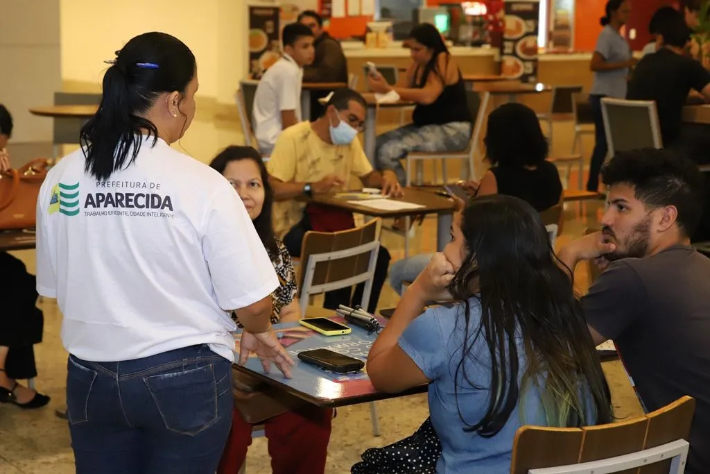 Candidatos preenchendo formulários e conversando com atendente no Espaço Aparecida, Aparecida Shopping