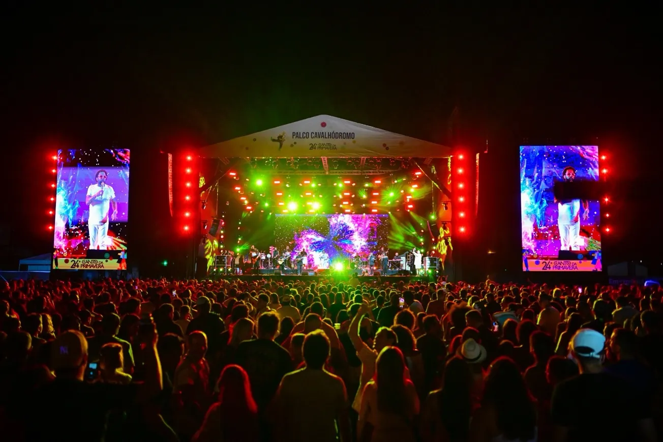 Palco iluminado do festival Canto da Primavera com público em Pirenópolis à noite