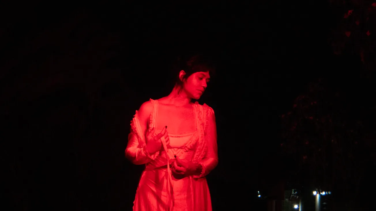 Brunê em performance iluminada por luz vermelha