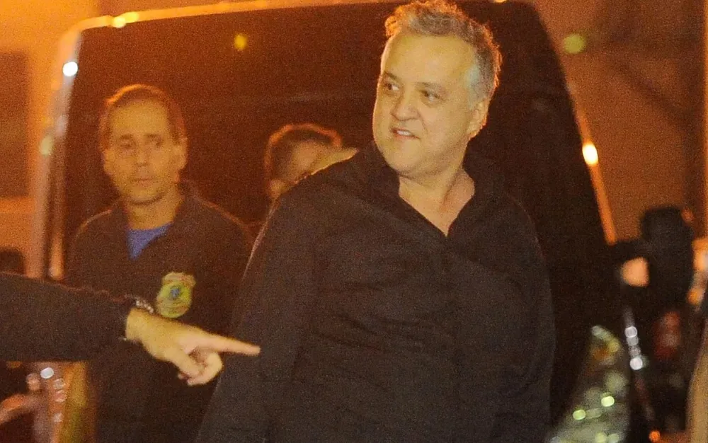 Carlinhos Cachoeira sendo escoltado por agentes da Polícia Federal à noite
