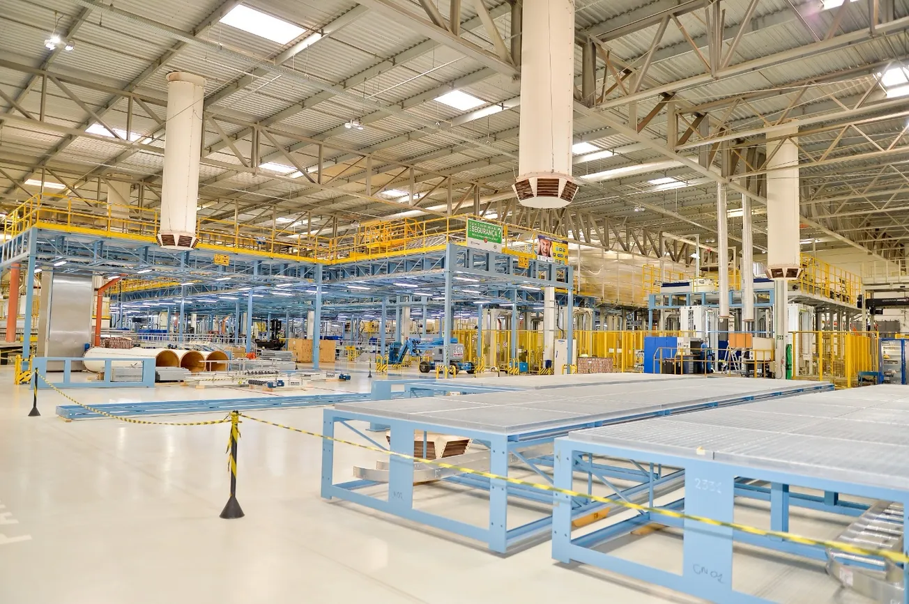 Interior de fábrica com estruturas metálicas, esteiras e equipamentos de produção