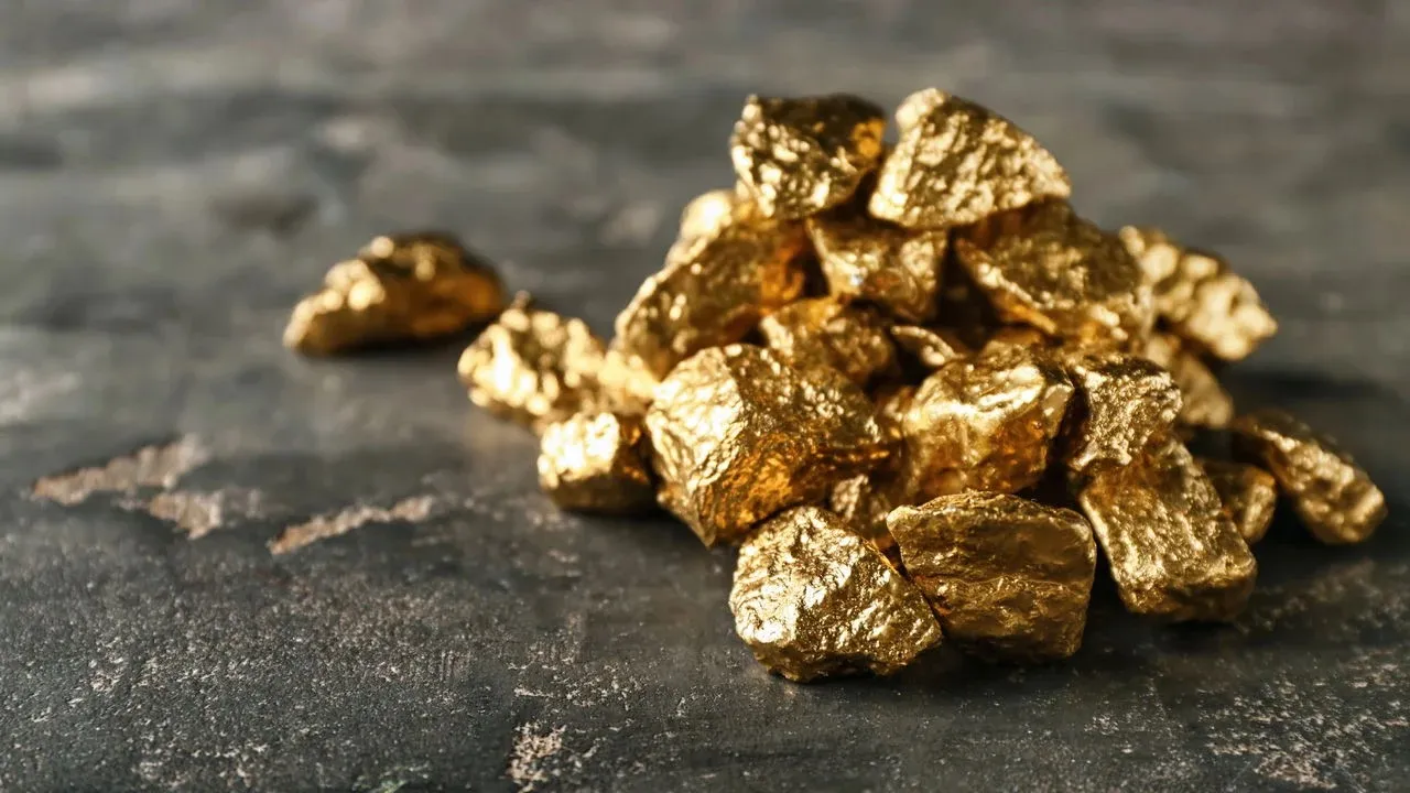 Pepitas de ouro sobre superfície escura, imagem ilustrativa